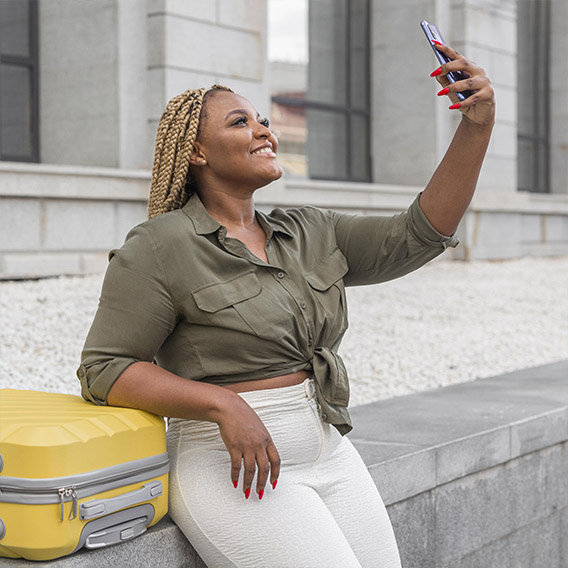 beautiful woman taking selfie her yellow luggage