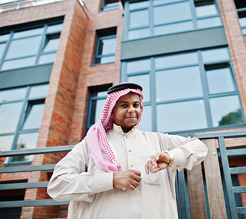 middle eastern arab man posed street against modern building looking his golden watches